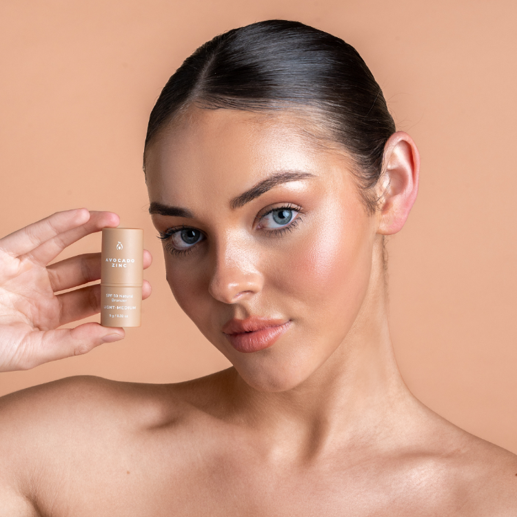 Woman holding a skincare product against a beige background