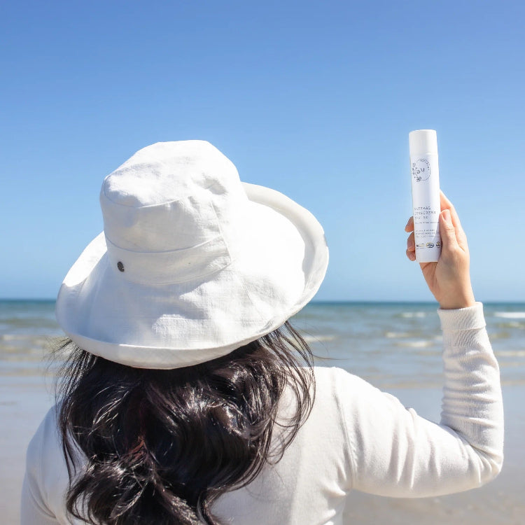 Person on a beach holding a bottle of sunscreen