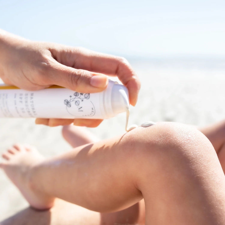 Person applying sunscreen to their leg with a sunny background