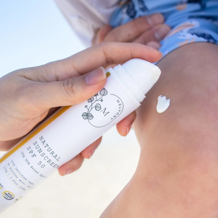Hand applying natural sunscreen to skin with a bottle.