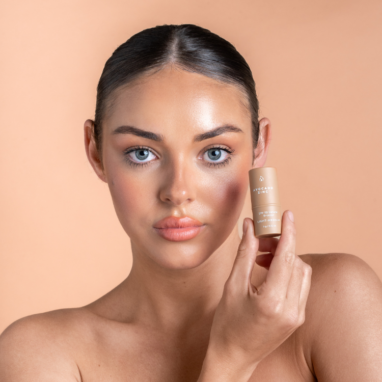 Woman holding a skincare product against a beige background